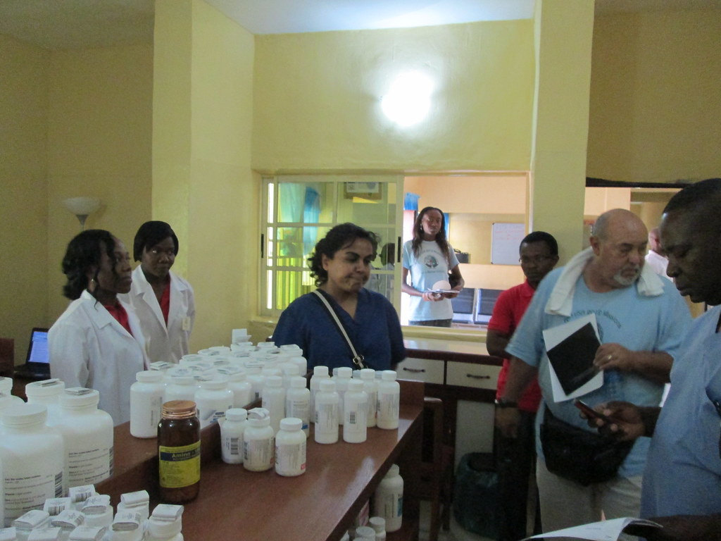 A pharmacy counter stocked with medicines, with health workers attending.