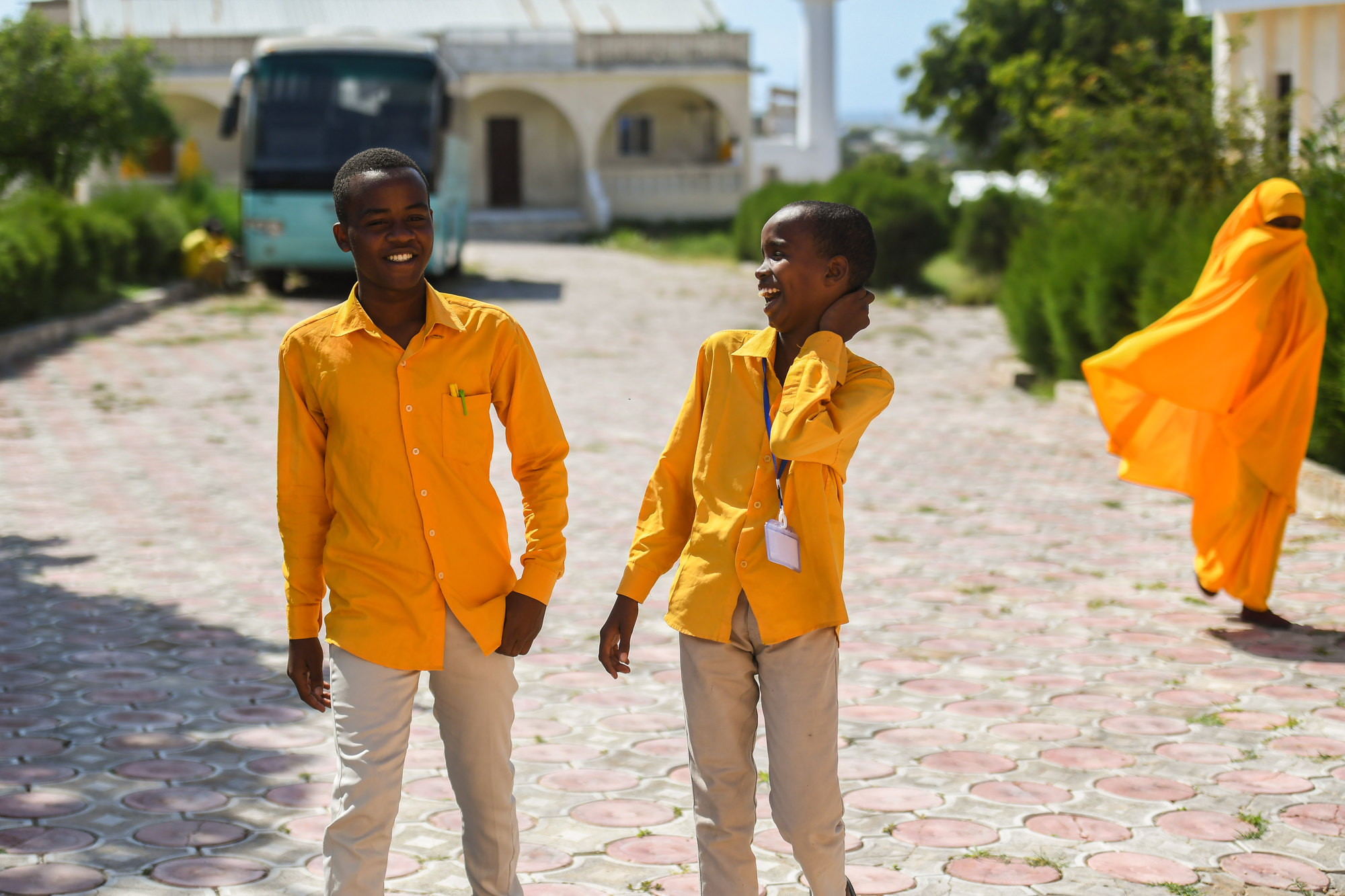 Two students in school uniform walking together and smiling.